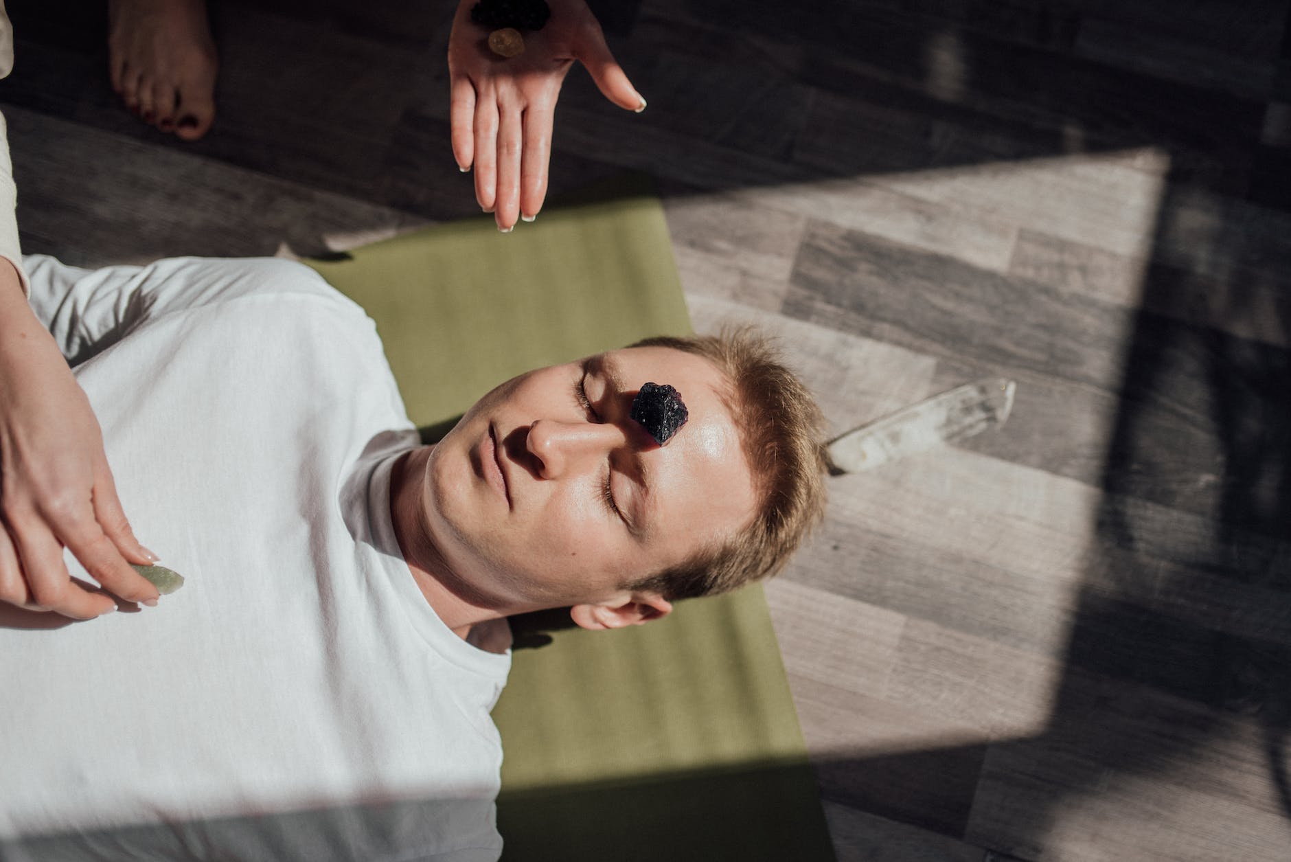 man lying down on floor with healing stone on forehead