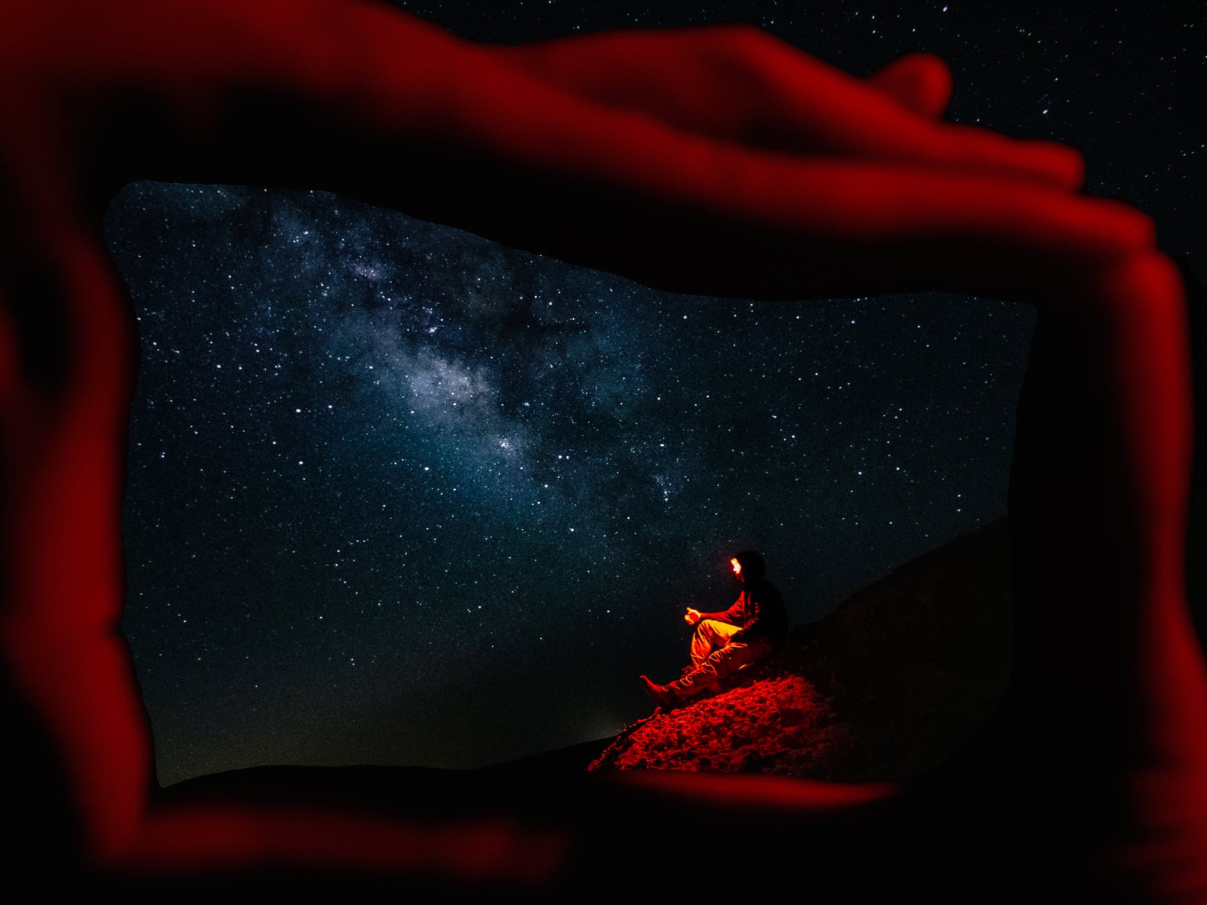person lying on rock under starry night